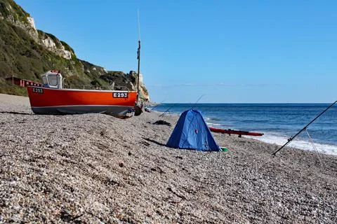 An old boat on the beach at Branscombe in Devon, England. Fishermen's equipme Stock Photos
