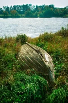 Old boat in the grass by the river Stock Photos