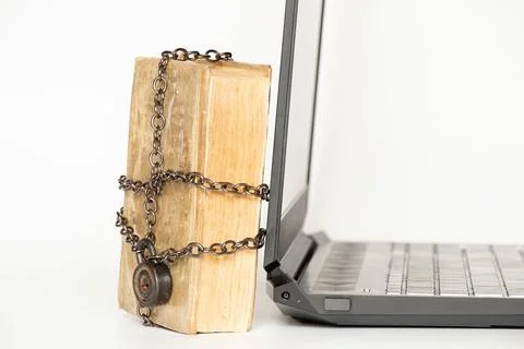 Old book in chains next to modern laptop on white background 写真素材