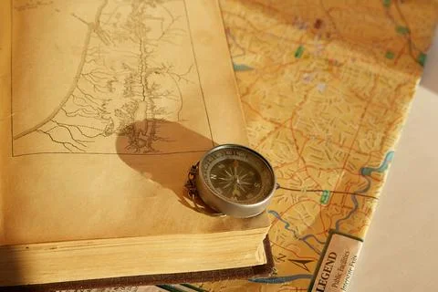 Old book, compass and map in the sunlight, old and modern maps, pilgrimage an Stock Photos