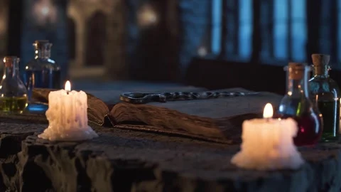 Old book, flickering candles, and elixirs set in a medieval interior Stock Footage 313115391