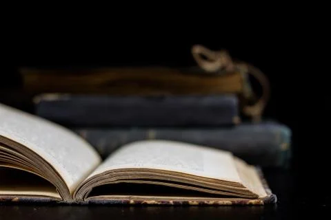 An old book lying on a black table. In the background a pile of old chunks. B Stock Photos