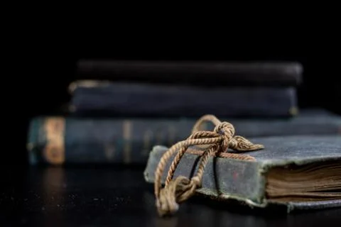 An old book lying on a black table. In the background a pile of old chunks. B Stock Photos