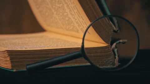 Old Book is Opened by a Girl Next to a Magnifying Glass Stock Footage 177330911