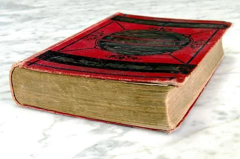 Old book with red binding on the marble table Stock Photos