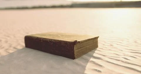 Old book resting on soft sand under warm sunlight near a calm shoreline Stock Illustration