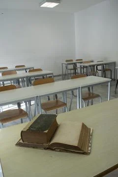 Old books on desk in empty classroom Stock Photos