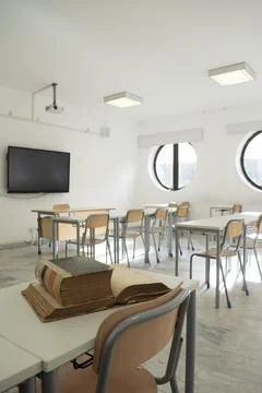 Old books on desk in empty classroom Stock Photos