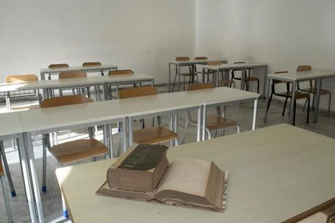 Old books on desk in empty classroom Stock Photos