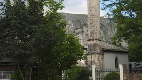 Old Bosnian Mosque Seen Between Two Green Trees, Tilt Down Stock Footage 231140526