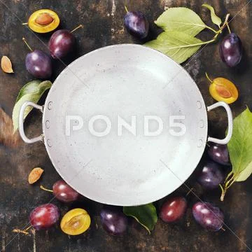 Old bowl and plums on a rural background Stock Photos