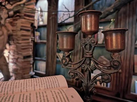 An old brass candlestick set against a background of bookcases Stock Photos
