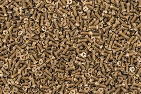 Old brass countersunk head screws with a phillips head screwdriver. Texture, Stock Photos