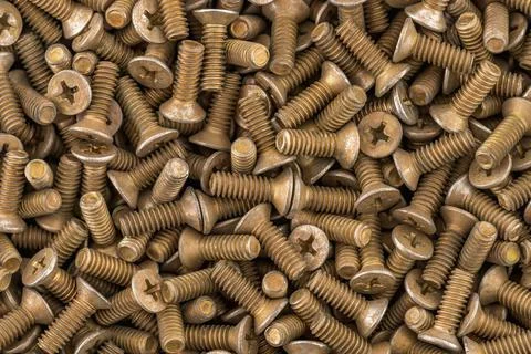 Old brass countersunk head screws with a phillips head screwdriver. Texture, Stock Photos