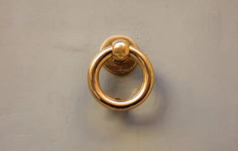 Old brass door knocker, ring shape, on a gray painted front door Stock Photos