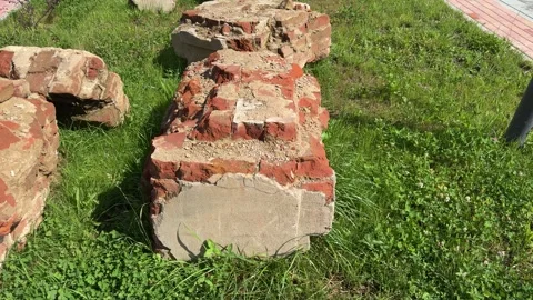 Old brick and concrete foundation remnants on green grass Vídeos de archivo 344041604