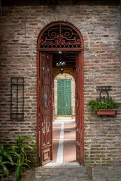 Old brick arch with rusty iron open gate, leading to a passage with a green Stock Photos
