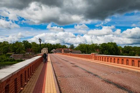 Old brick bridge over Venta river in Kuldiga, Latvia. Summer time and heavy Stock Photos