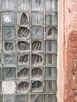 Old brick building facade with broken glass blocks showing signs of decay a.. Stock Photos