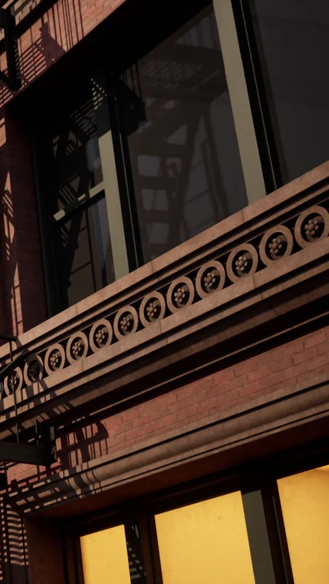 Old brick building with fire escape and yellow windows during the day Stock Footage 338421912