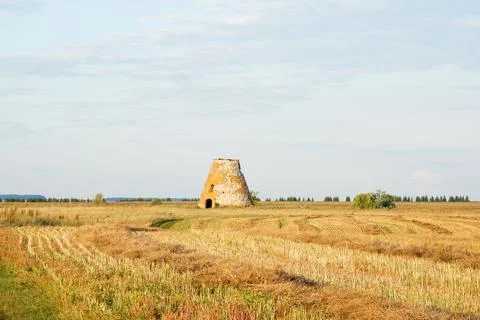 An old brick building stands alone in a field. Stock Photos