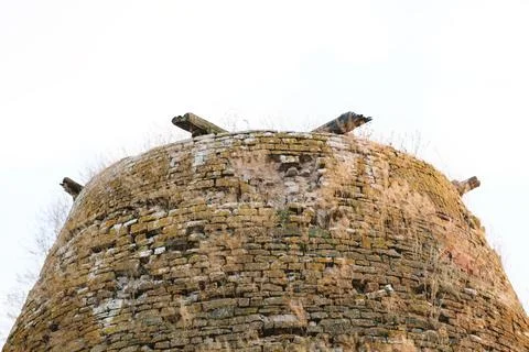 An old brick building stands alone in a field. An old dilapidated mill Stock Photos