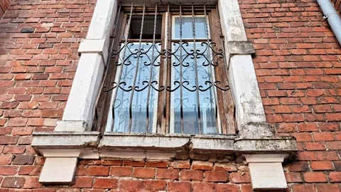 Old Brick Building Window with Ornate Iron Bars and Stone Frame 動画素材 347117535