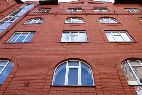 Old brick building with windows under a blue sky in a city Stock Photos