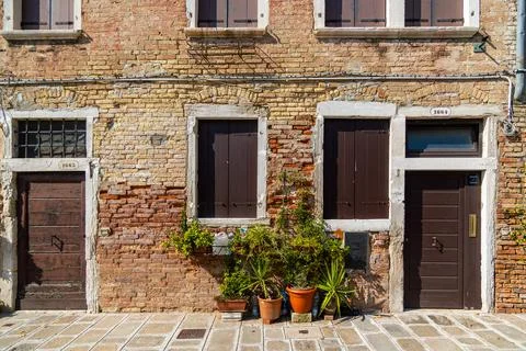 Old brick facade with shuttered windows and potted plants. Charming old building Stock Photos