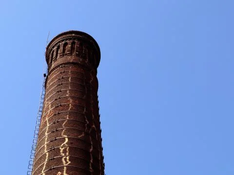Old brick factory smoke stack against blue sky, bottom view Stock Photos