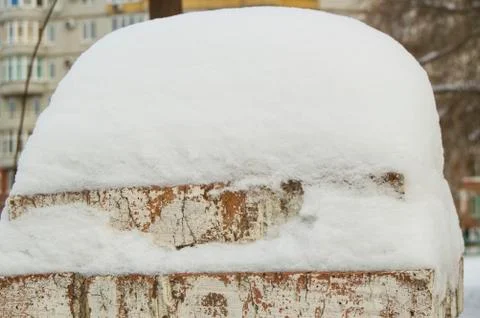 On an old brick post with cracked plaster lies a large snowdrift, a winter ba Foto stock