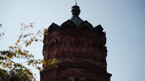 Old brick tower with onion dome under autumn leaves Video stock 347535674