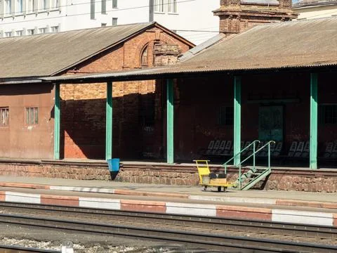 An old brick train station platform with metal seats and a luggage trolley, Stock Photos