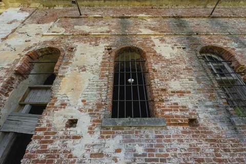 Old brick wall with arched windows and iron bars Stock-Fotos