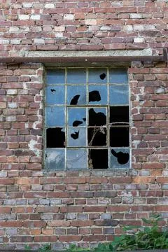Old brick wall with a broken multi-pane window, symbolizing urban decay and.. Stock Photos