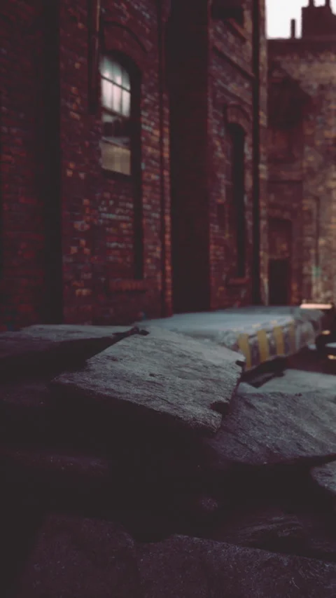 Old brick wall with broken pavement in an urban area at dusk Stock Footage 343155319