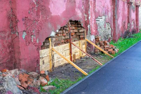 An old brick wall covered with plaster is falling apart and it is being repai Foto stock