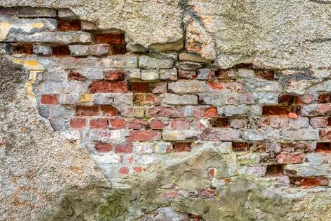 Old brick wall with crack, cement and plaster peel off. Background, texture. Stock Photos