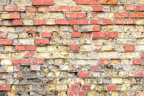 An old brick wall in a crumbling state with fragments of brickwork. Stock Photos