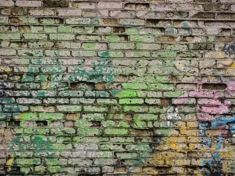 Old brick wall with multi-colored traces of paint Stock Photos