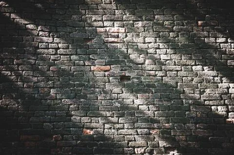 Old brick wall with rays of sun on it, urban background. Stock Photos