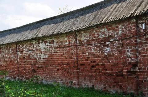 Old brick wall. Red brick wall with a wooden conical roof. Stock Photos