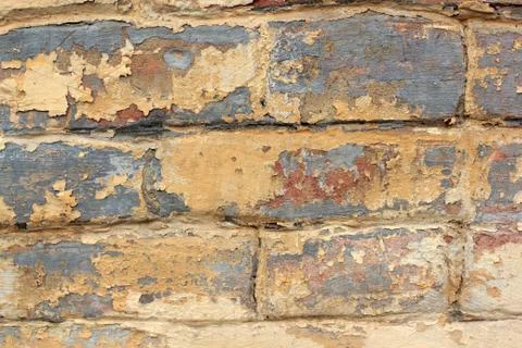 Old brick wall with remnants of yellow and red paint Stock Photos