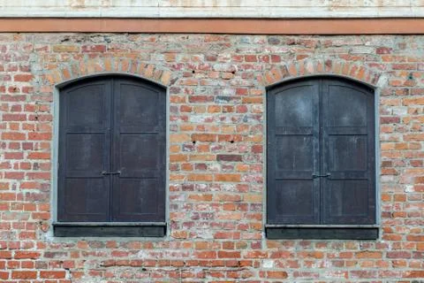 Old brick wall, two black shutter windows Stock Photos
