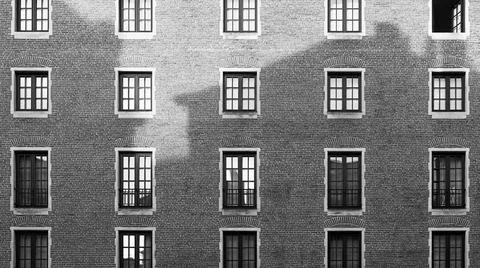 Old brick wall with windows and shadow of another building at sunset in black Stock Photos