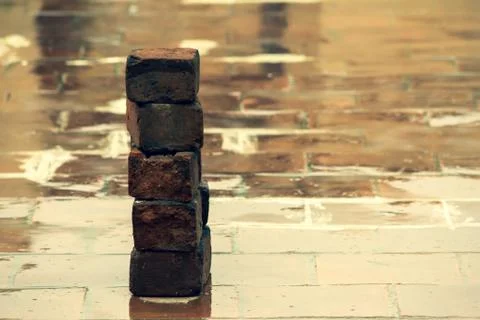 Old bricks used in construction stacked over one another on wet floor Stock Photos