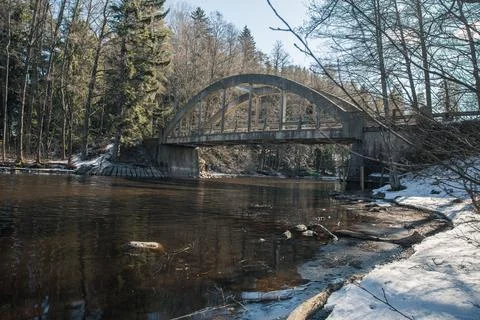 Old bridge across the river Spring landscape in April of a forest river. Snow Stock Photos