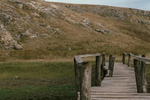 Old bridge made of boards on a field near the Moldavian rocky mountains Stock Photos