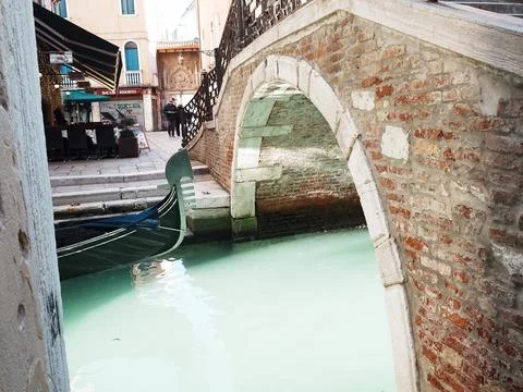 An old bridge oder a small canal in Venice, Italy. The water is glowing Stock Photos