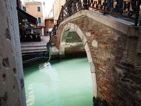 An old bridge oder a small canal in Venice, Italy. The water is glowing Stock Photos